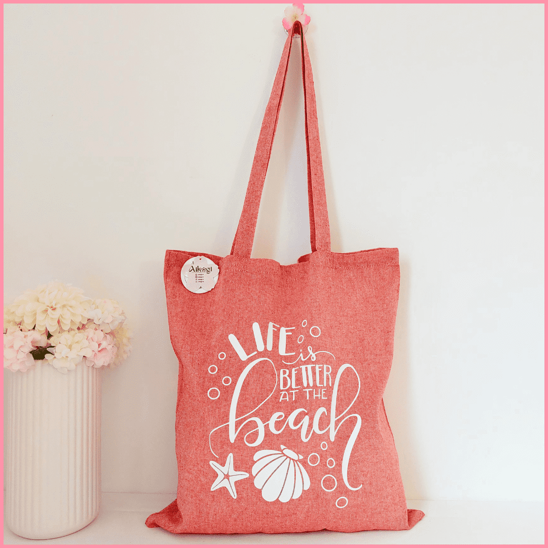 Tote bag color rojo con diseño de elementos del mar como conchas, estrellas y burbujas y la frase Life is better at the beach