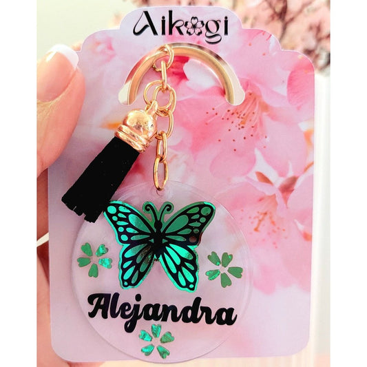 Llavero acrílico personalizado transparente con nombre en negro y diseño de mariposa verde con borla negra 