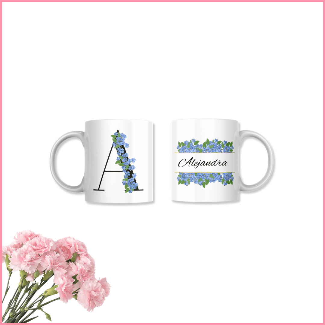 presentación de taza personalizada con inicial y nombre y flores azules sobre un ramo de flores rosas