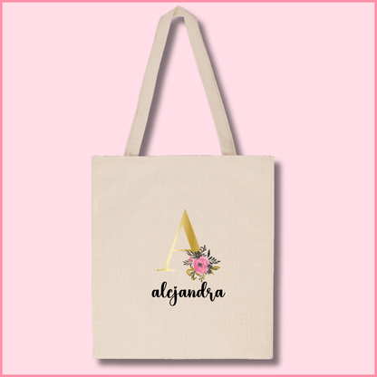 Tote bag de poliéster beige personalizada con la inicial en color dorado y flor rosa