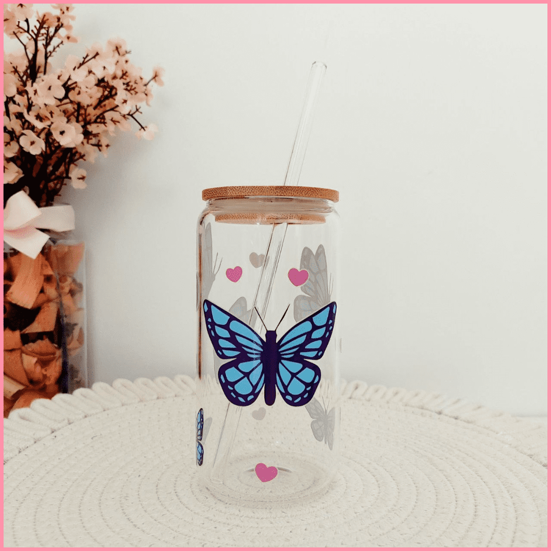 Vaso de vidrio con tapa de bambú y pajita con diseño de mariposas azules y corazones rosas